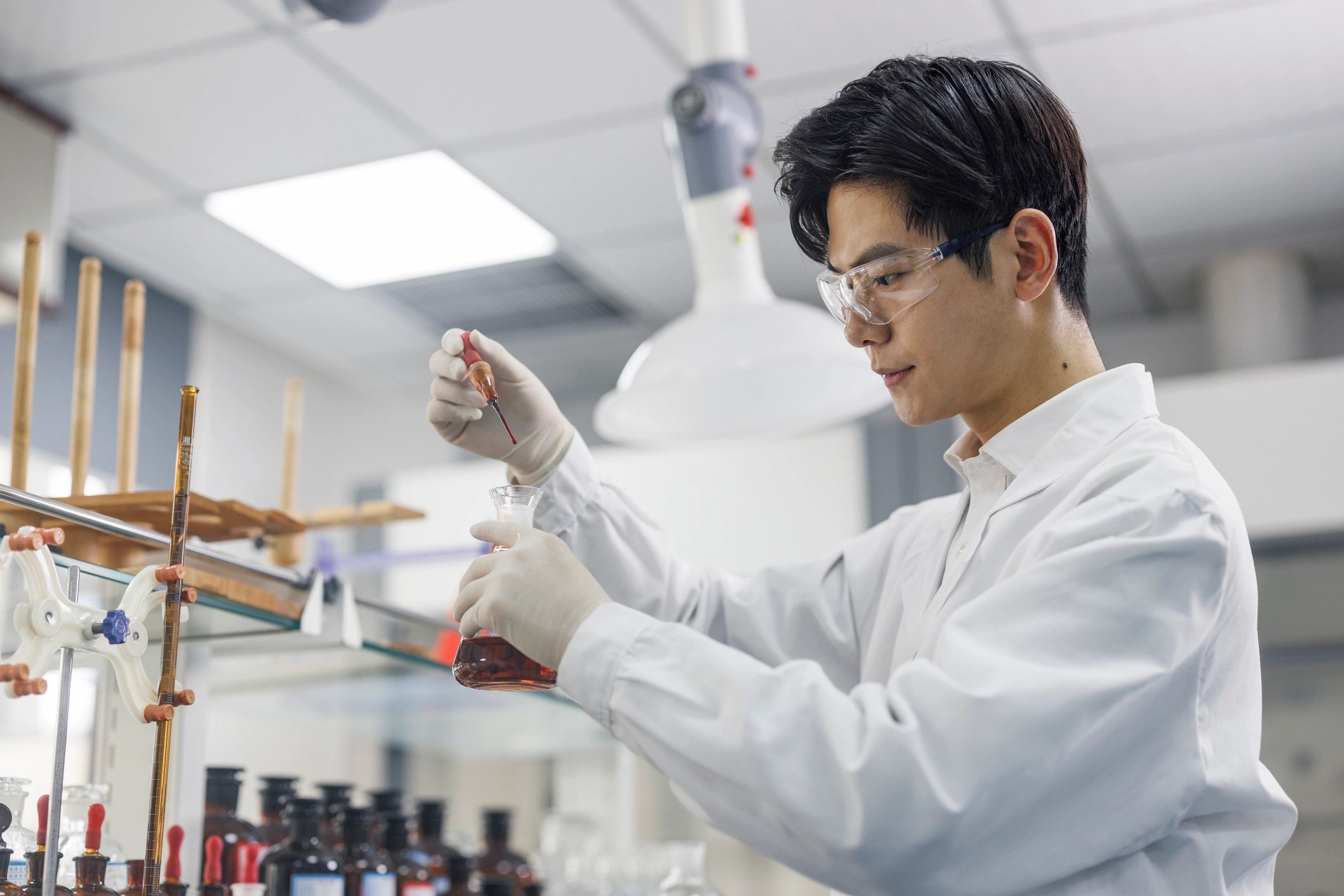 Scientist performing laboratory testing with pipette and glassware